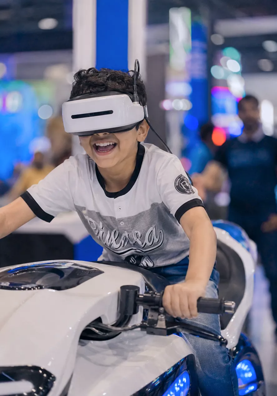 child-wearing-a-vr-headset-sits-on-gaming-equipment-at-an-interactive-entertainment-exhibit